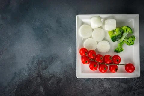 Vegetable minimalistic composition: Cherry tomatoes, onions, broccoli on a wh 스톡 사진