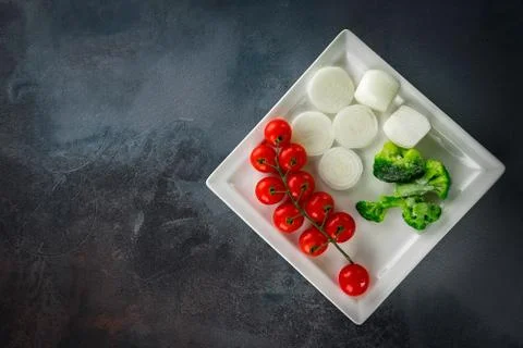 Vegetable minimalistic composition: Cherry tomatoes, onions, broccoli on a wh Stock Photos