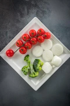 Vegetable minimalistic composition: Cherry tomatoes, onions, broccoli on a wh 库存照片