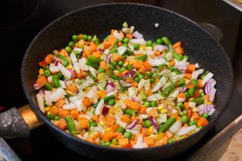 Vegetable mixture in a pan on a glass-ceramic stove Stock Photos