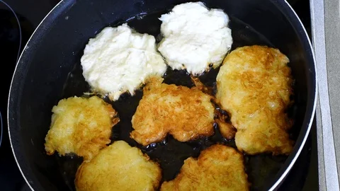 Vegetable pancakes are cooked in vegetable oil in a frying pan Stock Footage 94450153