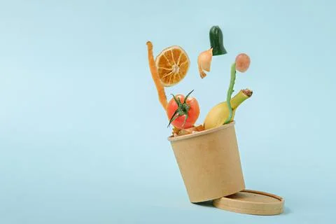 Vegetable peels in compost bin with levitation effect on blue background, com Foto stock