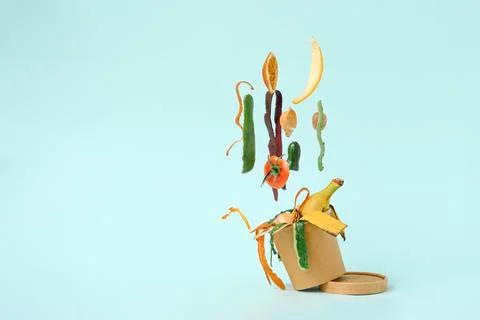 Vegetable peels in compost bin with levitation effect on blue background, com Stock Photos