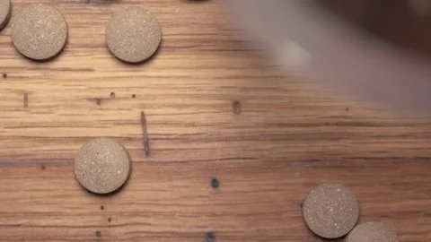 Vegetable pills pour and fall on a wooden table Video stock 168642321
