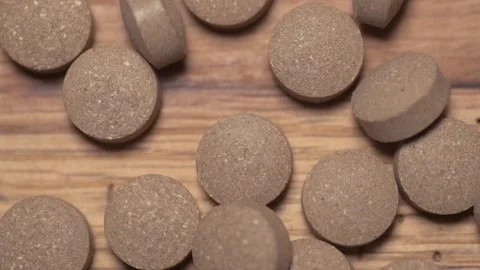 Vegetable pills pour and fall on a wooden table Video stock 168642536