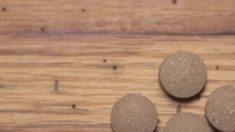 Vegetable pills pour and fall on a wooden table Video stock 168642677