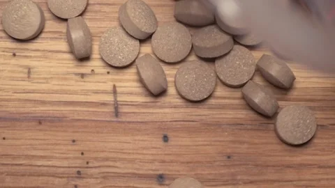 Vegetable pills pour and fall on a wooden table Video stock 168643060