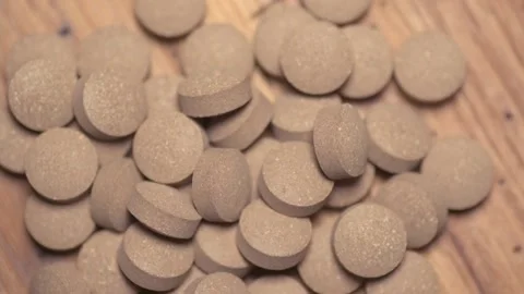 Vegetable pills pour and fall on a wooden table Video stock 168643172