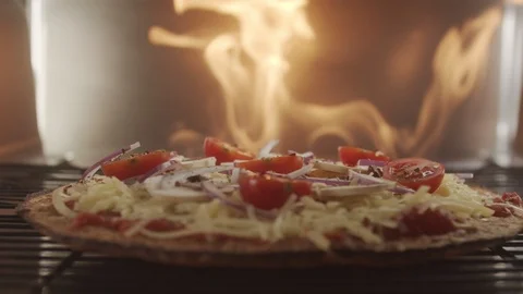 Vegetable pizza with cherry tomatoes set to cook in the oven with blazing fire Video stock 123364306
