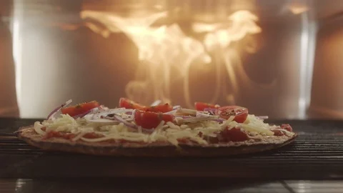 Vegetable pizza with cherry tomatoes set to cook in the oven with blazing fire Stock Footage 123366673