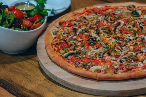 Vegetable pizza served with fresh side salad Stock Photos