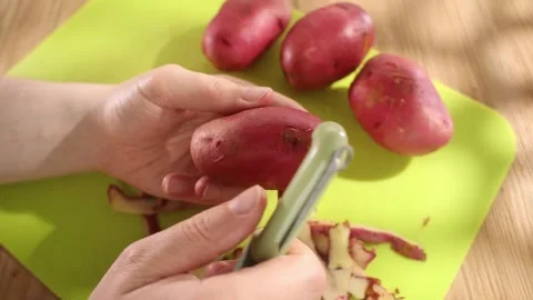 Vegetable preparation. men's hands are peeling potatoes. close-up. sunny day. Stock Footage 244444543