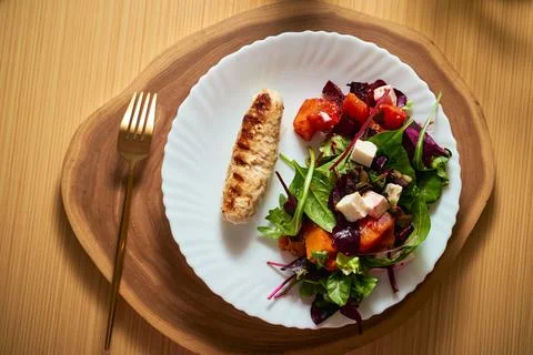 Vegetable salad with beetroot and pumpkin on a white plate with grilled chick Stock Photos