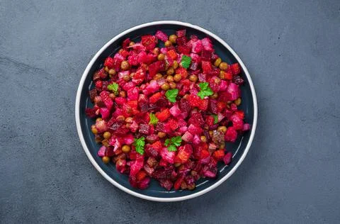 Vegetable salad with beetroot, pickled cucumbers, peas and fresh herbs on a dark Stock Photos