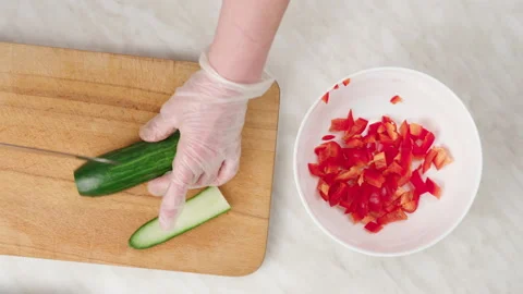 Vegetable salad. Cut a fresh cucumber into cubes on a wooden board. 库存影片 148930863