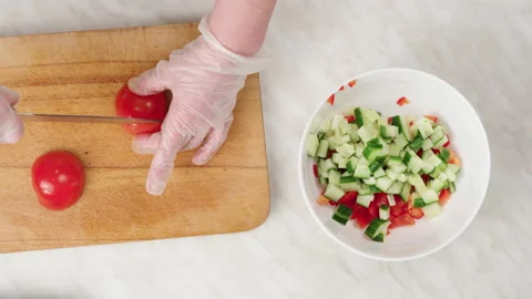 Vegetable salad. Cut a fresh tomato into cubes on a wooden board. Stock Footage 148930797