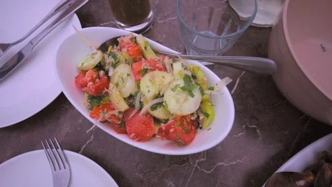 Vegetable salad with tomatoes and cucumbers in white plate in restaurant, Video stock 276619726