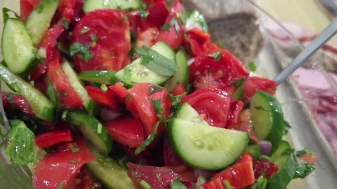 Vegetable salad with tomatoes, cucumbers, red peppers, and herbs in a glass bowl Stock Footage 297612053