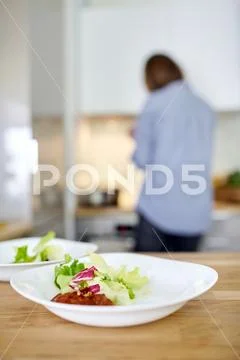 Vegetable salad in a white plate on a wooden table, cooking in a home kitchen Stock Photos