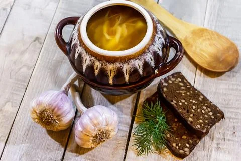 Vegetable soup in a pot with bread and fresh garlic on a gray wooden backgrou Stock Photos