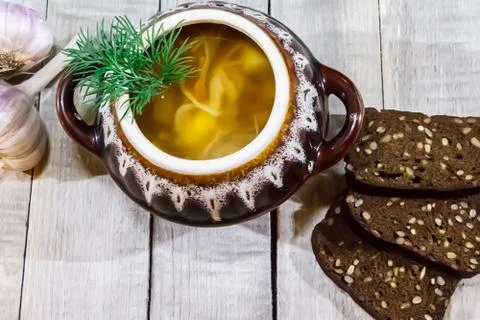 Vegetable soup in a pot with bread and fresh garlic on a gray wooden backgrou Foto stock