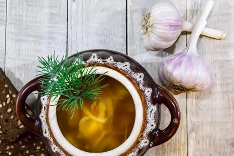 Vegetable soup in a pot with bread and fresh garlic on a gray wooden backgrou Stock Photos