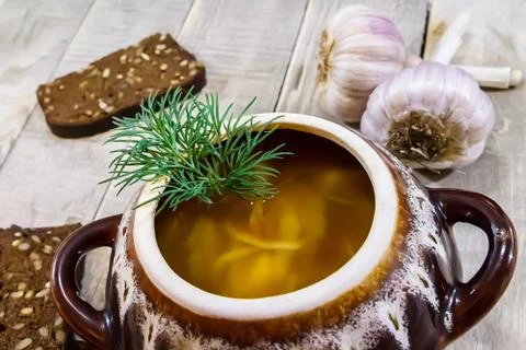 Vegetable soup in a pot with bread and fresh garlic on a gray wooden backgrou Stock Photos