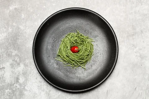 Vegetable spaghetti with a cherry tomato in a black plate Stock Photos