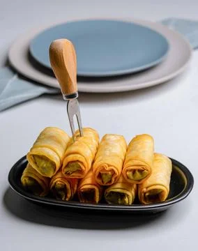 Vegetable spring rolls arranged in a black tray with wooden fork Stock Photos