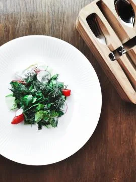 Vegetable spring salad with poached egg in beautiful white porcelain plate on a Stock Photos