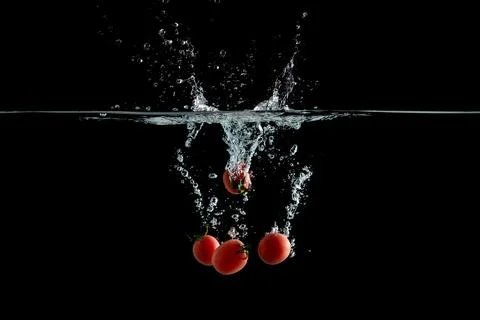 Vegetable tomatoes falling water high speed photograph Foto stock