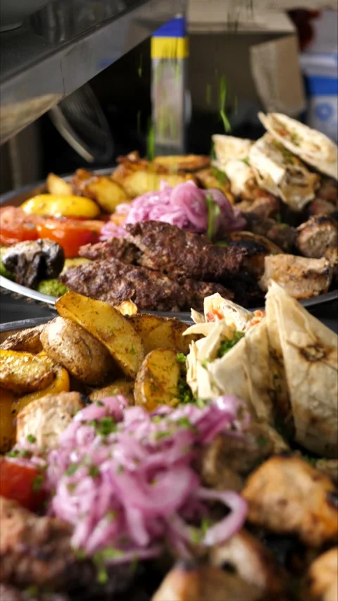 Vegetables and grilled meat on a plate sprinkled with herbs before serving Stock Footage 306364140