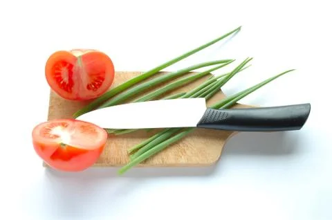 Vegetables and knife on chopping board on white background Stock Photos