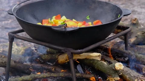 Vegetables are fried in a cauldron over a fire. Stewing vegetables on the fire Stock Footage 278868727