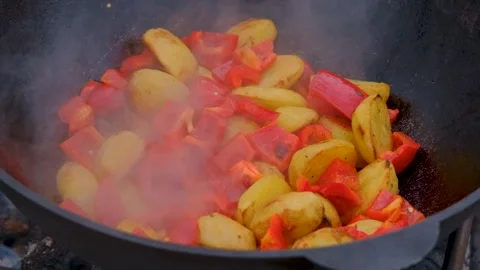 Vegetables are fried in a cauldron over a fire. Stewing vegetables on the fire Stock Footage 280213747