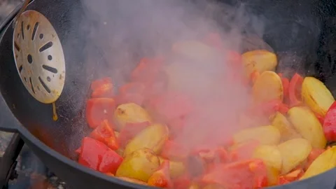 Vegetables are fried in a cauldron over a fire. Stewing vegetables on the fire Stock Footage 280928721