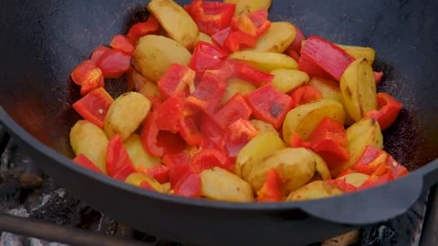 Vegetables are fried in a cauldron over a fire. Stewing vegetables on the fire.  Stock Footage 282829425