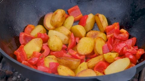 Vegetables are fried in a cauldron over a fire. Stewing vegetables on the fire.  Stock Footage 282829544