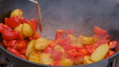 Vegetables are fried in a cauldron over a fire. Stewing vegetables on the fire.  Stock Footage 283629336