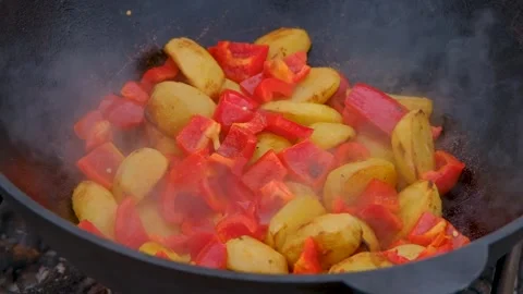 Vegetables are fried in a cauldron over a fire. Stewing vegetables on the fire.  Stock Footage 283629337