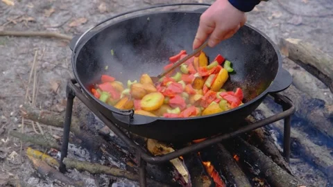 Vegetables are fried in a cauldron over a fire. Stewing vegetables on the fire.  Stock Footage 283630017