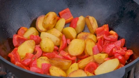 Vegetables are fried in a cauldron over a fire. Stewing vegetables on the fire Stock Footage 307313763