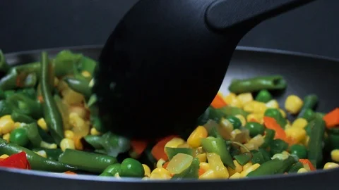 Vegetables are fried in a frying pan. The cook interferes with the spoon Stock Footage 89841852