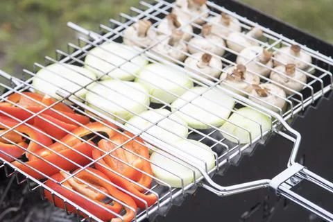 Vegetables are fried on a wire rack on an iron grill. Pepper, zucchini, mushroom Stock Photos