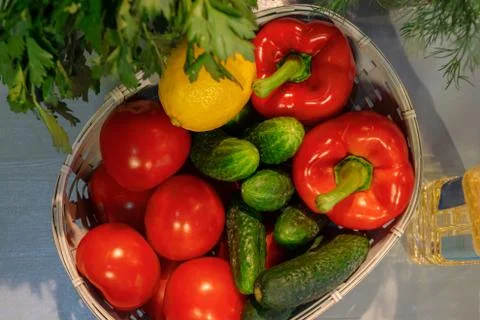 Vegetables in a basket next to bunches of herbs on the kitchen table. Foto stock