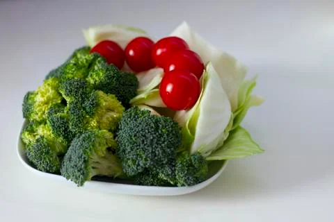 Vegetables (cabbage, tomato, broccoli) on a white plate on a white table Stock Photos