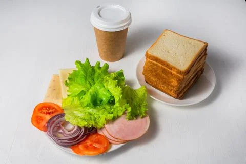 Vegetables, cheese, ham and bread are prepared for sandwiches. A cup of coffe Stock Photos