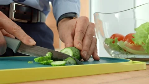 Vegetables cooking. Cucumbers cutting process. A man holds a vegetable in his Stock Footage 138837036