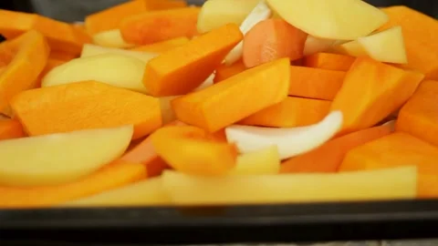 Vegetables drop onto a baking tray for baking. Brightly colored pumpkin, carrots Stock Footage 314982810
