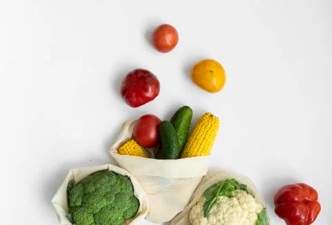 Vegetables in eco bag on white surface. Pepper, tomato, corn, cucumber, broccoli Stock Photos